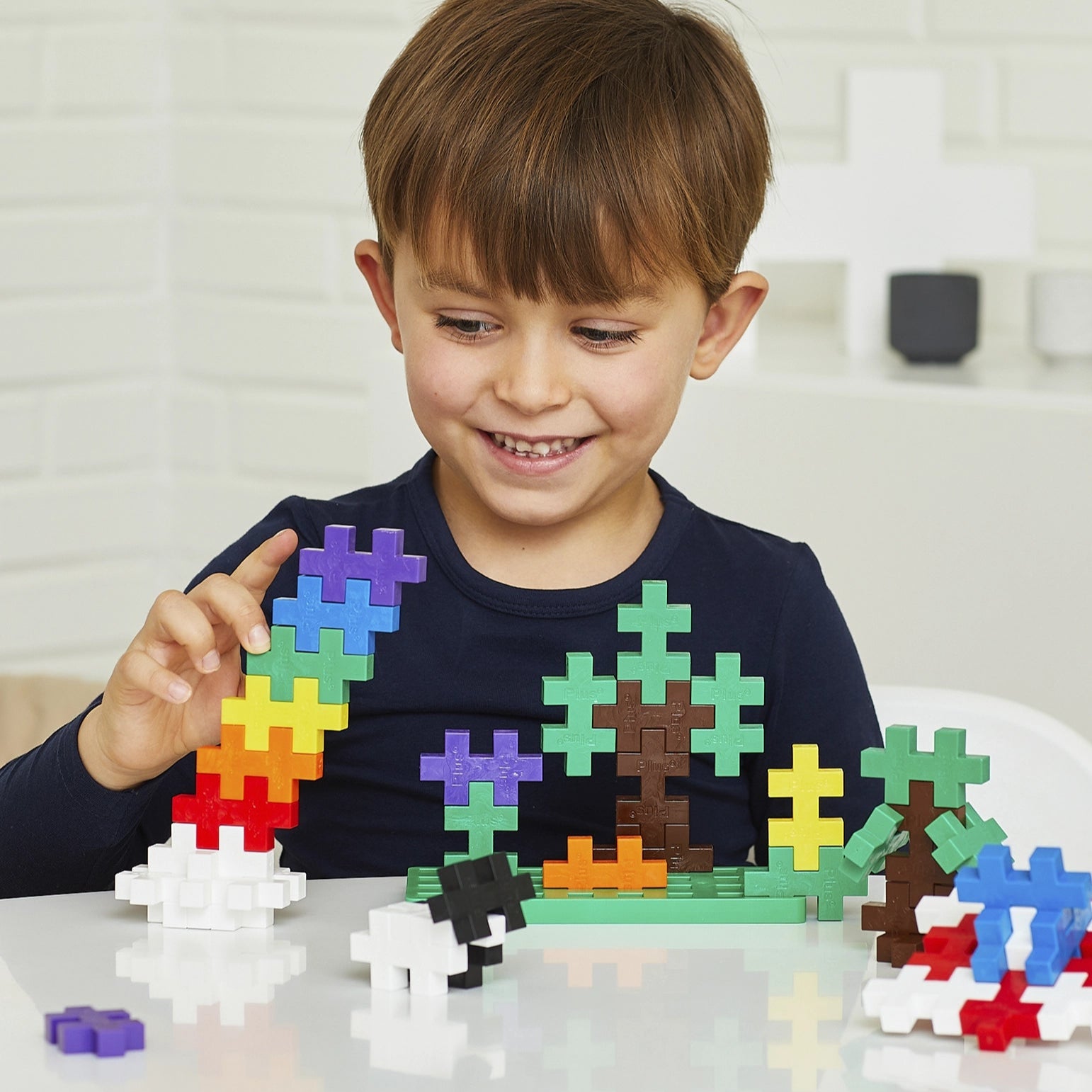 Child playing with colorful building blocks on a white surface